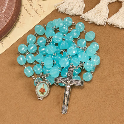 con una catenina in lega rosata, perline blu a forma di cubo, con l'icona della Madonna e un crocifisso
