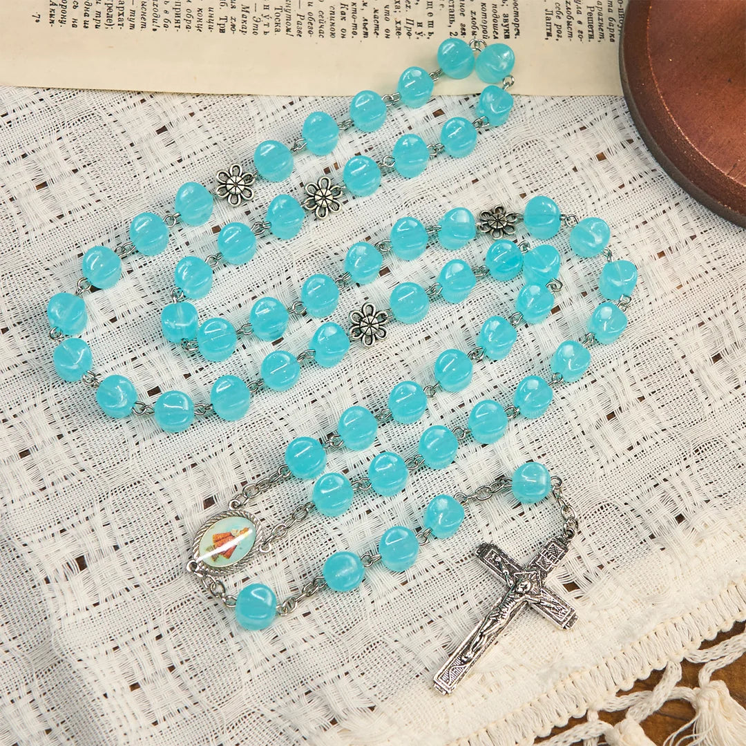 con una catenina in lega rosata, perline blu a forma di cubo, con l'icona della Madonna e un crocifisso