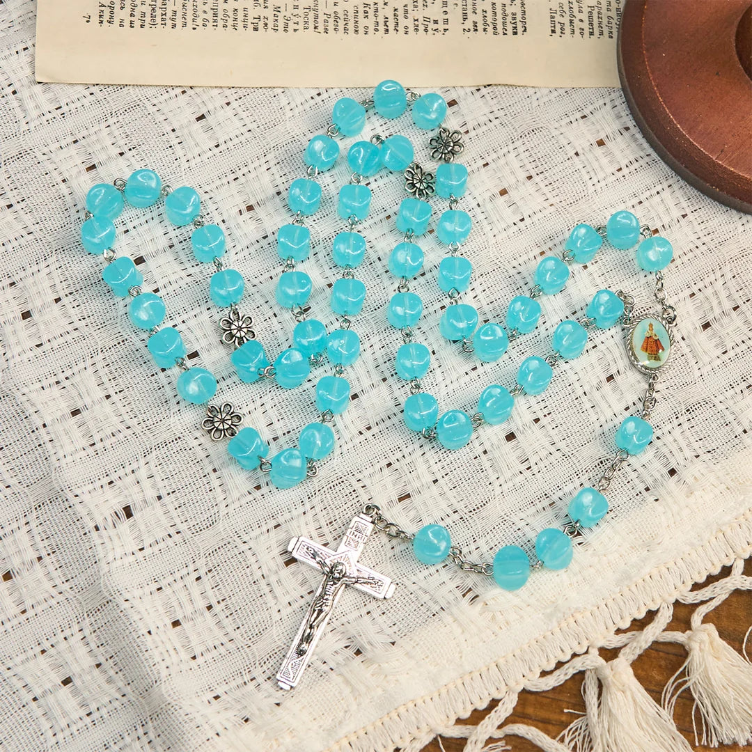 con una catenina in lega rosata, perline blu a forma di cubo, con l'icona della Madonna e un crocifisso