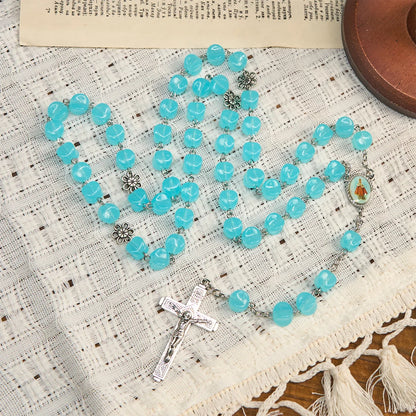 con una catenina in lega rosata, perline blu a forma di cubo, con l'icona della Madonna e un crocifisso