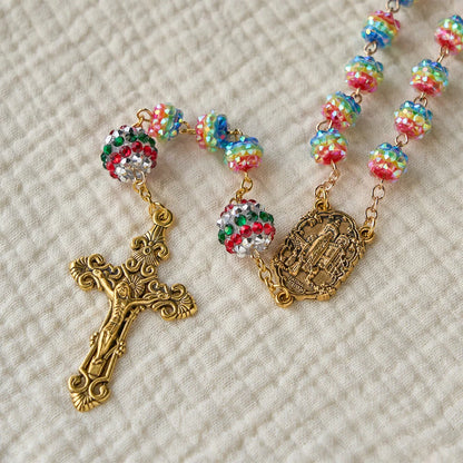 Rosario con perline arcobaleno a tema natalizio e croce dorata: devozione e fede viva