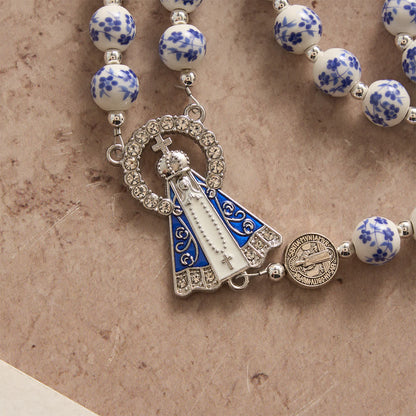 Rosario in ceramica Sacrelle nei colori bianco e blu con motivo floreale, medaglie di San Benedetto e della Madonna