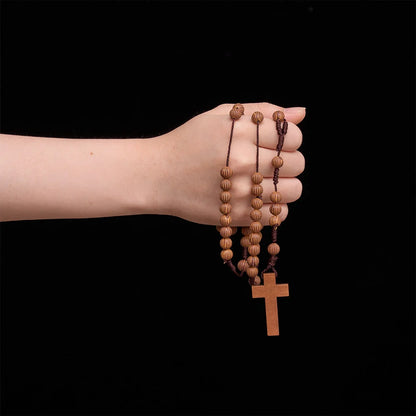 Rosario intrecciato in corda scura effetto legno con pendente a forma di croce: simbolo di un ornamento religioso essenziale