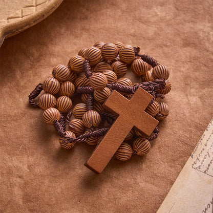 Rosario intrecciato in corda scura effetto legno con pendente a forma di croce: simbolo di un ornamento religioso essenziale