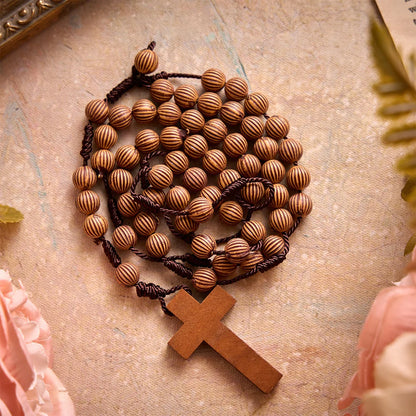 Rosario intrecciato in corda scura effetto legno con pendente a forma di croce: simbolo di un ornamento religioso essenziale