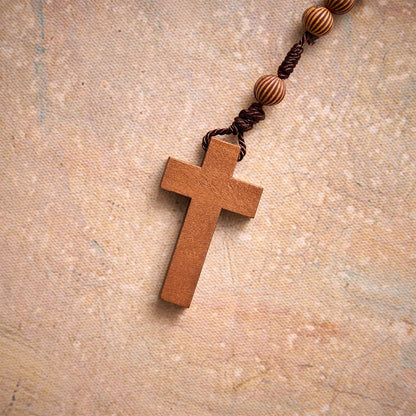 Rosario intrecciato in corda scura effetto legno con pendente a forma di croce: simbolo di un ornamento religioso essenziale