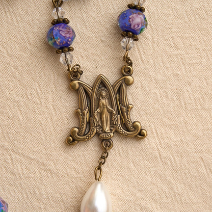 color antico con perline di vetro blu a forma di fiore, con una medaglia della Madonna e un crocifisso dettagliato