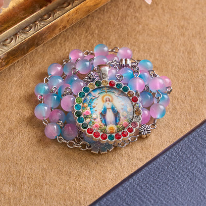 Rosario decorativo con medaglia della Madonna Miracolosa e grani in vetro: segno di protezione divina